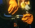 Divator yellow mask, on a rig incorporating our Dive-gas management manifold, which is ideal for alternating gas supplies, whether using mixed gases, or simply a twin air pack. All controls are ventral and (usually, barring photography) tucked away, neatly mounted on the diver's webbing but readily accessible to a gloved hand; safely operated without having to look at the valve wheels. Note the Divator Sport regulator, in the left hand - usually this is tucked away for emergency rescue purposes; controlled through the Dive-gas manifold.
A careful look, near the diver's eyes, reveals the special lugs, built in to the mask, to accommodate its being fitted with prescription spectacles.